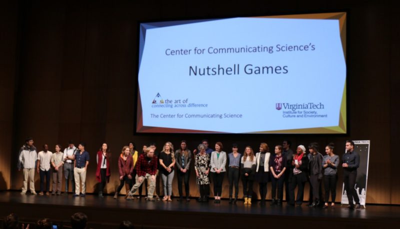 This photo shows a group of young adults lined up on a stage with a large screen behind them that reads Center for Communicating Science's Nutshell Games.
