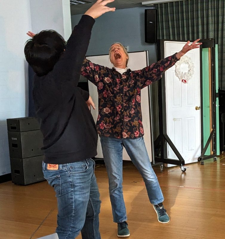 Two participants face each other, arms out in balletic flourishes.