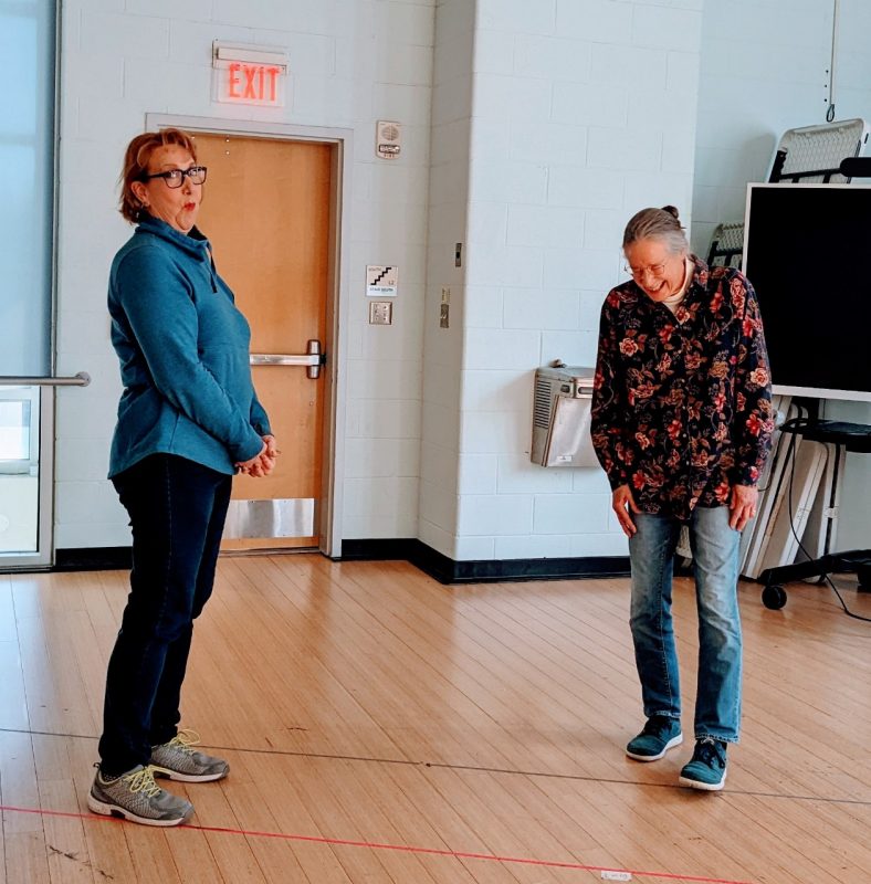 A participant looks at the camera while another laughs.