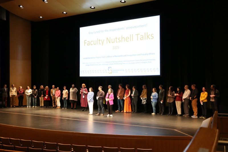 Participants, judges, and the three prize-winning presenters celebrate the Faculty Nutshell Talks on stage as the audience cheers.