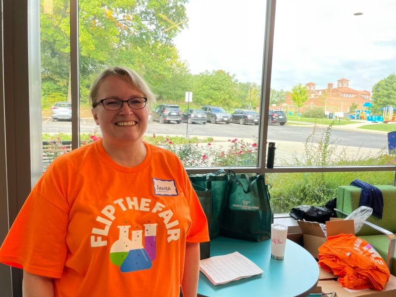 This photo shows Amanda Hensley, a smiling blonde woman with glasses wearing a Flip the Fair shirt.