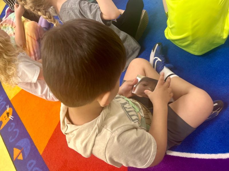 To demonstrate condensation, the high schoolers distributed mirrors, allowing the kindergarteners to observe how their breath creates fog when moisture condenses on the surface.