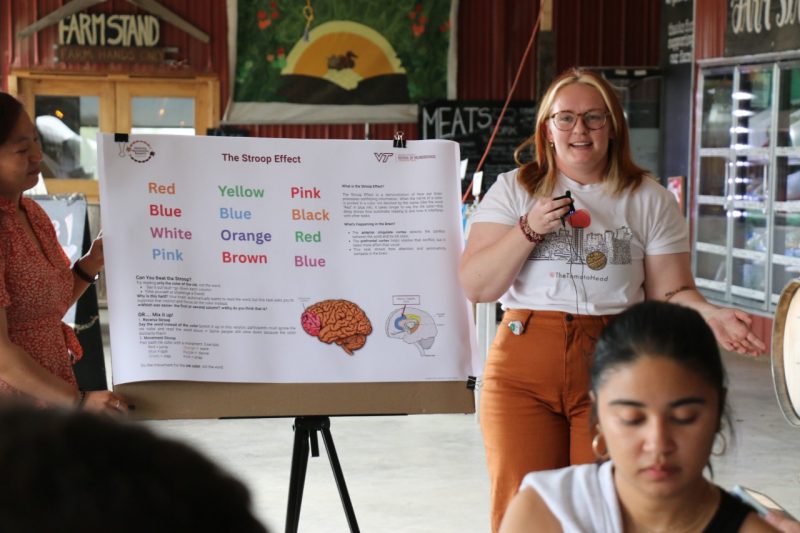 Alexis Mann talks next to a poster detailing the Stroop effect.