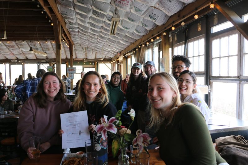A group of participants hold up their trivia sheet and smile at the camera.