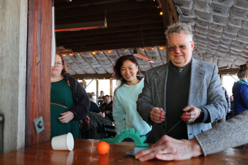 A participant puppets an arm, while two others look on behind him.