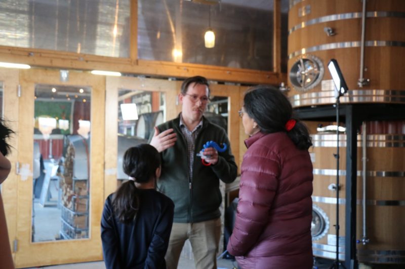Naughton speaks to a woman and child, whose backs are to the camera.