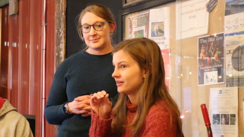 A participant speaks into a microphone as DeNunzio looks on.