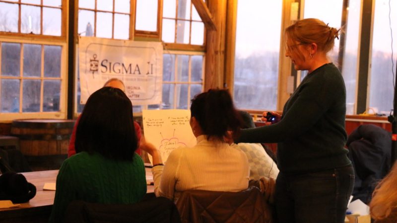 Maria DeNunzio gestures to a piece of paper that a participant holds up. Maria and the participant are shown from behind.