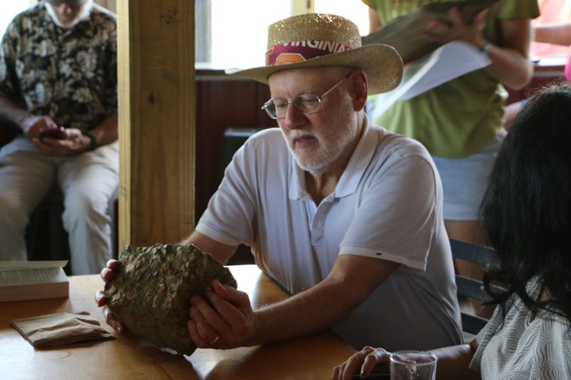 This photo shows a man studying a flat pebble conglomerate. 
