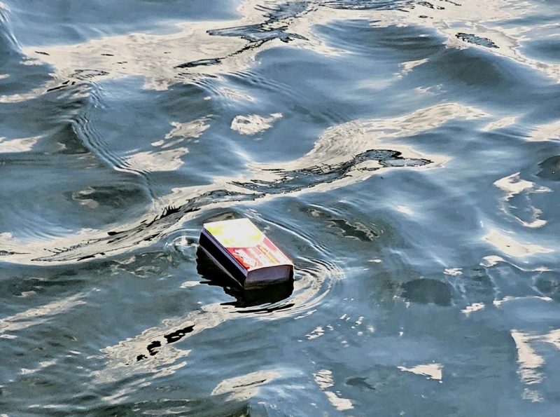 A matchbox floating on water, causing some rippling.