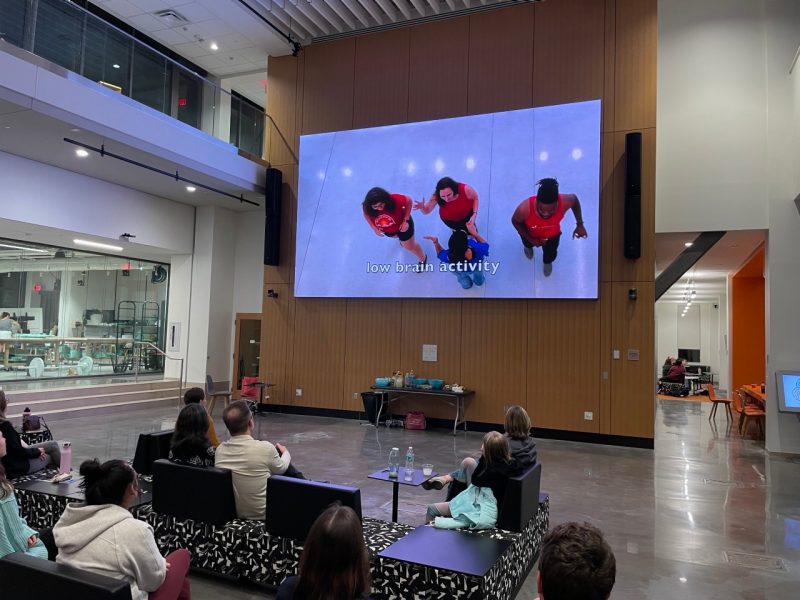 This photo shows an audience watching a video on a very large screen.