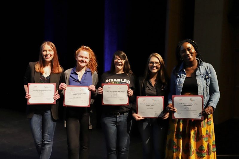 This photo shows five young women holding certificates and smiling at the camera. 