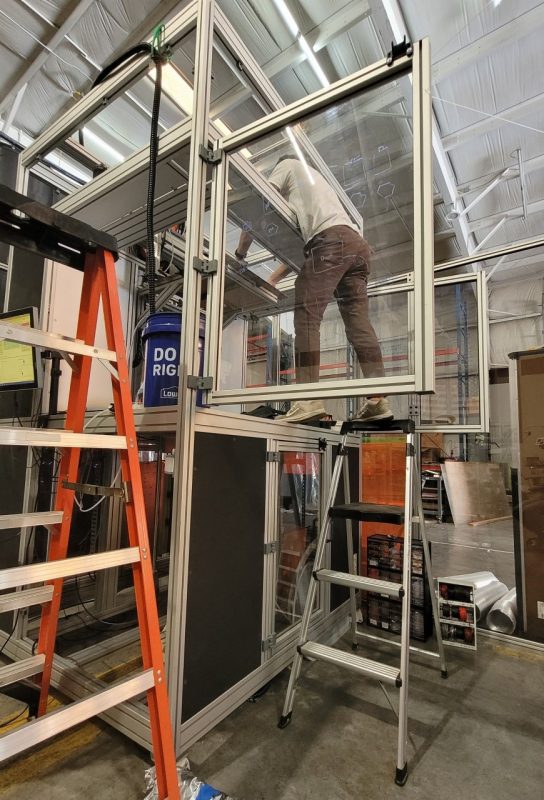3D printer A picture of a young male in a lab standing on top of a ladder checking a sample.