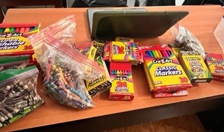 A pcture of crayons, markers, and zip lock bags of crayons on a desk. 