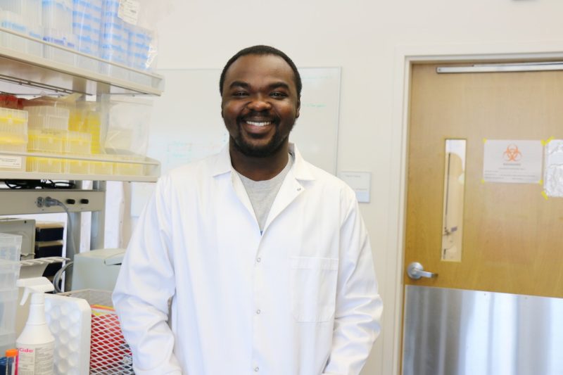 Martin smiling in his lab coat in the laboratory.