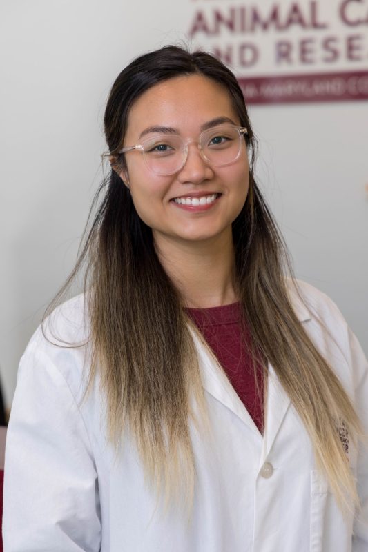Ny Luong stands, smiling at the camera, wearing a white lab coat.