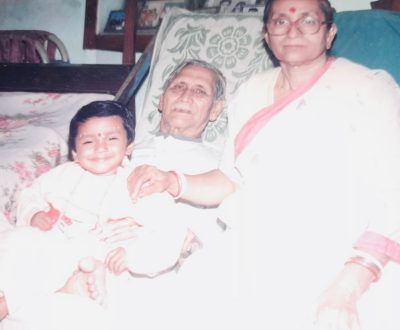 Photo shows a young child sitting with her grandparents in her family home.