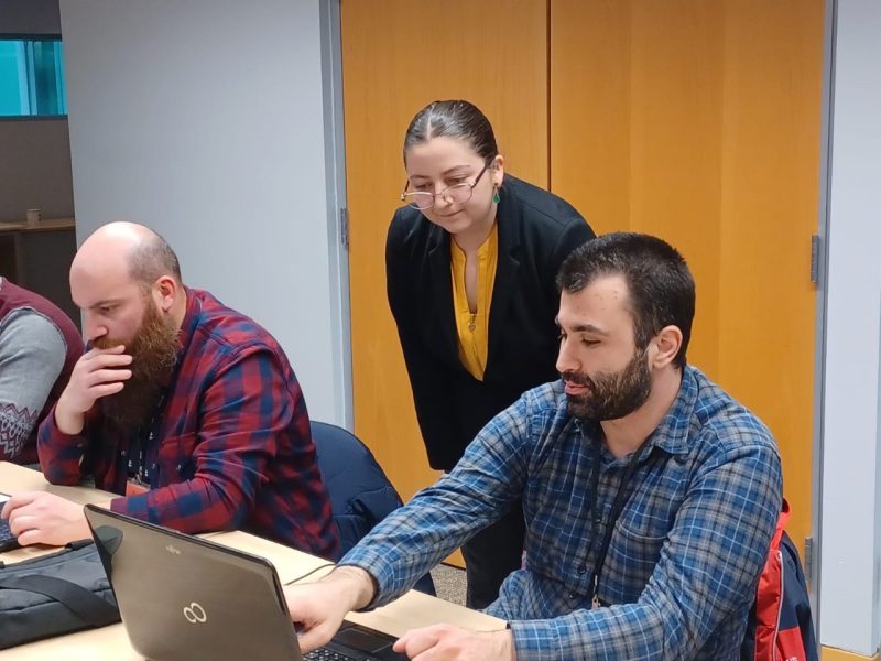 Mariana looks over the shoulder of a participant as she helps him with a project.