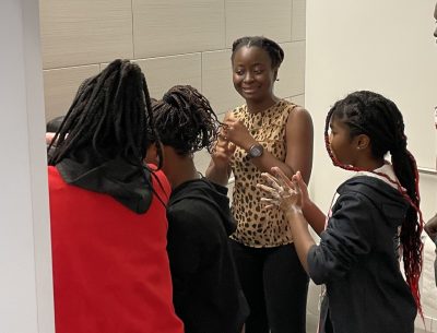 A picture of an adult women and three children washing their hands with soap. 