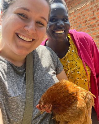 A picture of a young white woman holding a chicken next to a Black woman. 