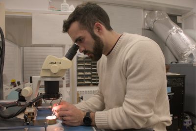 Graduate researcher Tristan Anderson uses a microscope to inspect the largest features of one of his devices.
