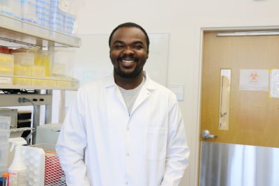 Martin smiling in his lab coat in the laboratory.