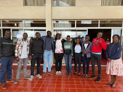 This photo show ten young Black Africans, both males and females, standing in a semi-circle and smiling at the camera or at one another.