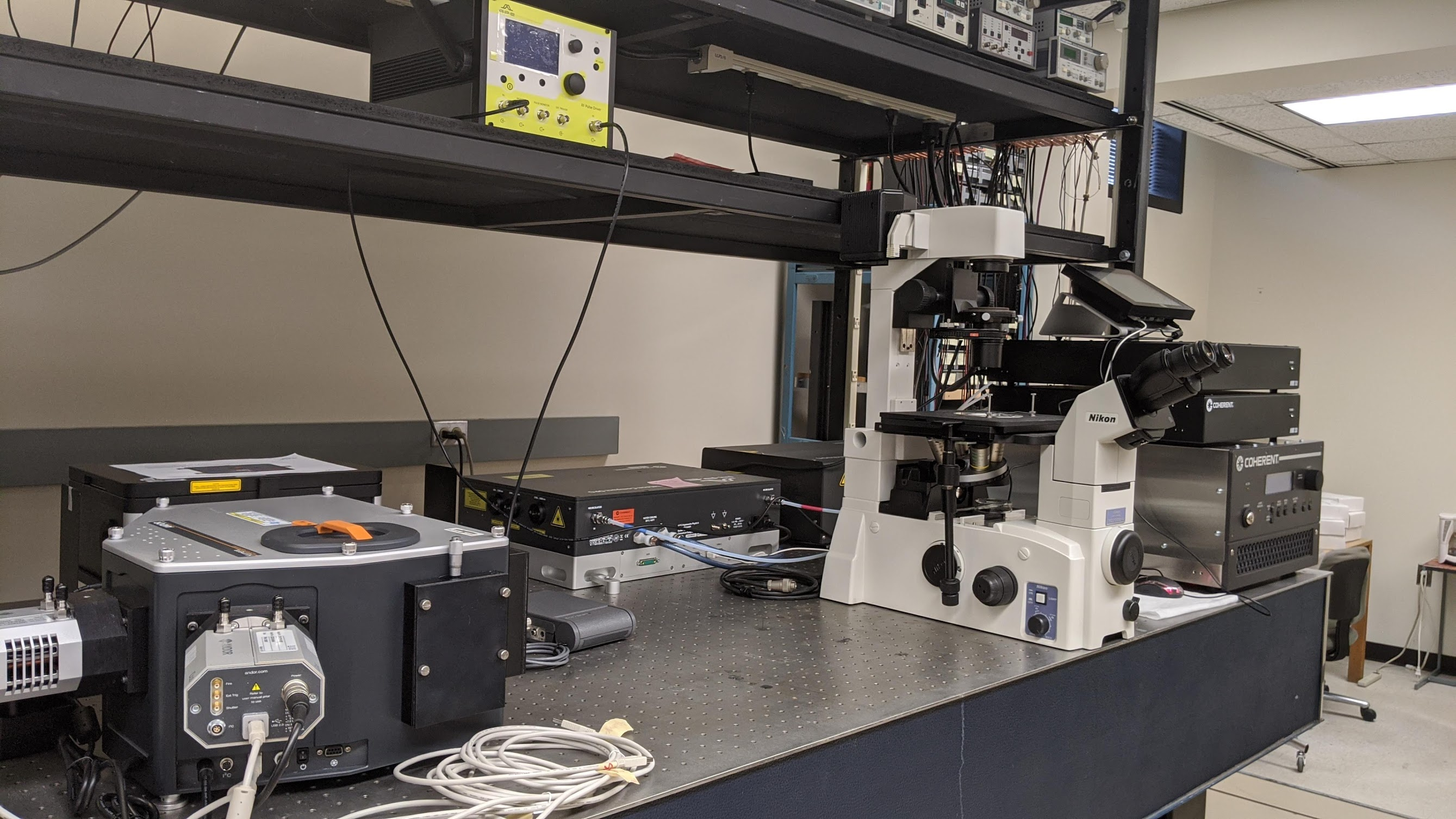This photo shows a laboratory bench with a high power microscope and other equipment on it.