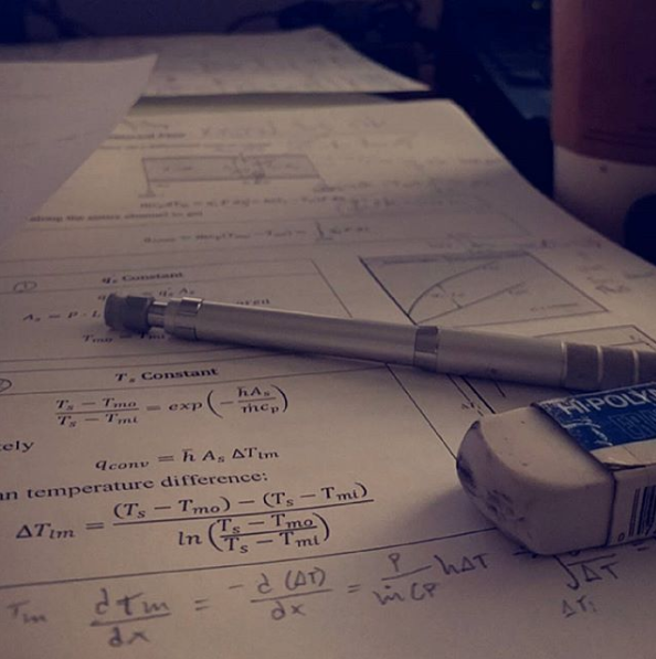 This photo shows an eraser and a mechanical pencil lying on a sheet of homework covered with both typed and written equations related to temperature.