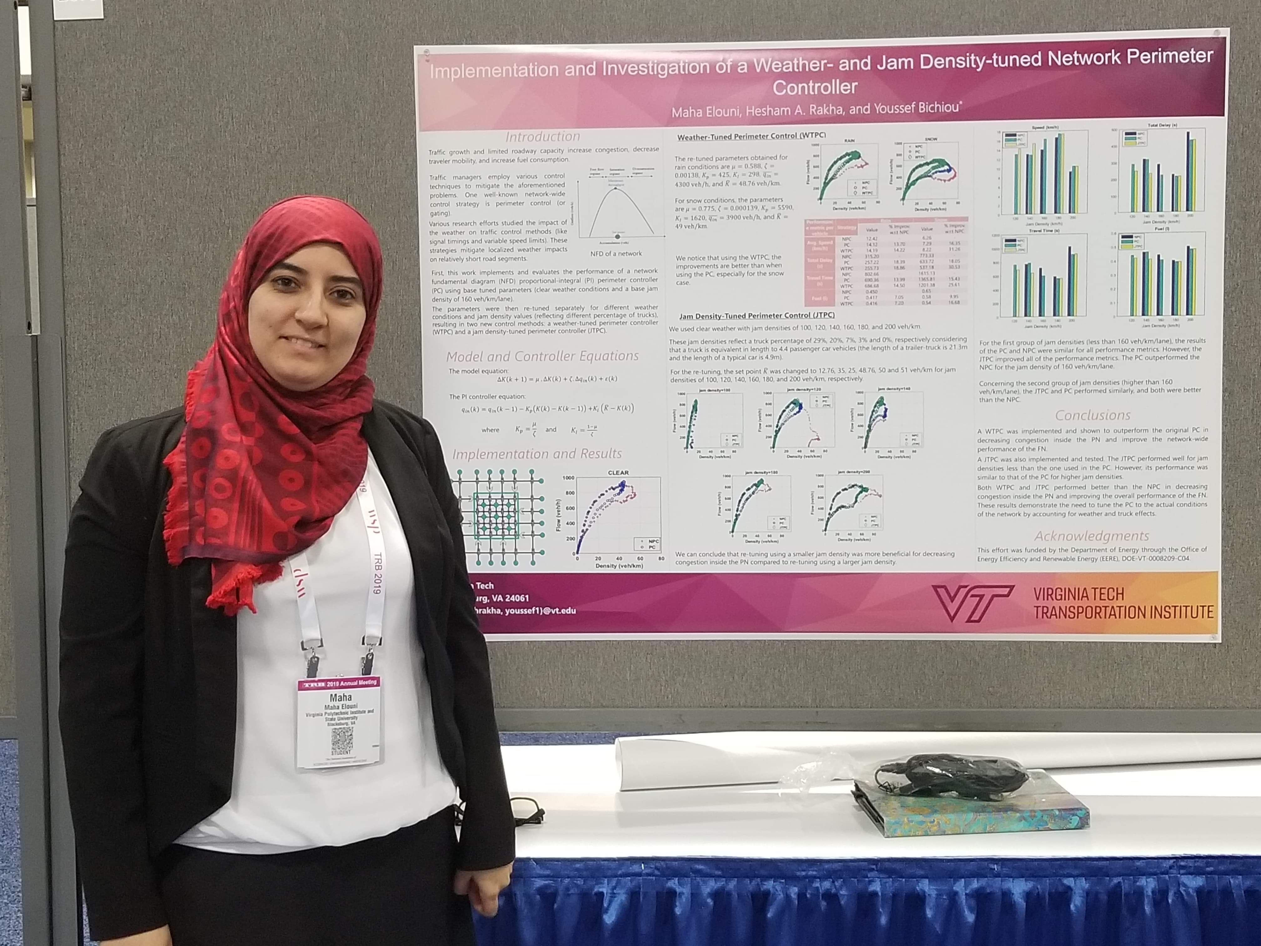 This photo shows a young woman in a black jacket, white blouse, and head head covering standing in front of a research poster covered with text, graphs, and bar charts.