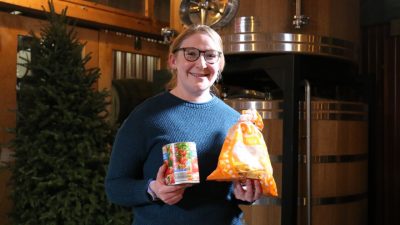 Maria DeNunzio holds up a bag of tortilla chips and a can of crushed tomatoes in each hand.